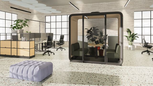 Gemütliche Büro-Loungezone mit gepolsterten Sesseln, Pflanzen, offenem Regalsystem und angrenzendem Konferenzraum.