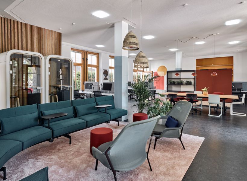 Offene Bürofläche mit Loungebereich, Besprechungstischen, schallgedämmten Arbeitskabinen und Pflanzen zur Gliederung unterschiedlicher Arbeitszonen.