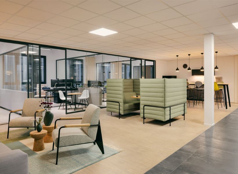Offene Bürofläche mit Lounge-Sitzgruppe, verglasten Besprechungsräumen und akustisch abgeschirmten Sitznischen für konzentrierte Gespräche und Zusammenarbeit.