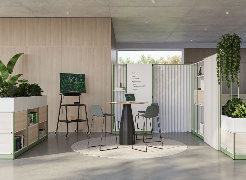 Freistehende Stellwände strukturieren eine offene Bürofläche zu einem informellen Besprechungs‑ und Rückzugsbereich.