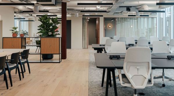 Modernes Großraumbüro mit Arbeitsplätzen, Besprechungstisch, Raumteilern und Pflanzen; offene Gestaltung mit flexibler Möblierung und Tageslicht.