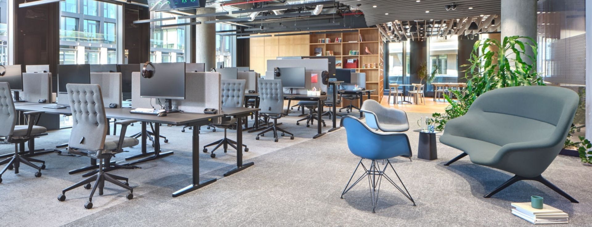 Open-Space-Büro mit höhenverstellbaren Arbeitsplätzen, zonierten Arbeits- und Loungebereichen sowie flexiblen Zonen für Austausch und Rückzug.