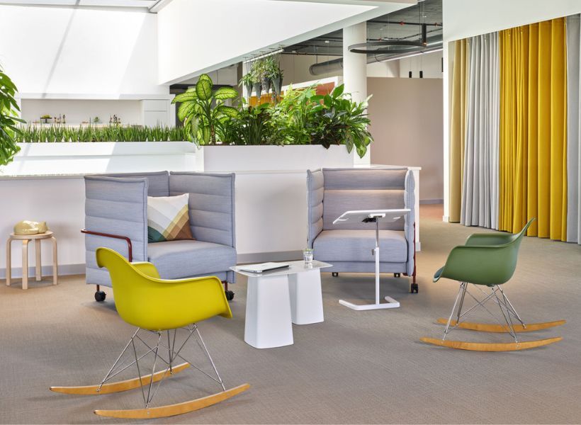 Farbig gestaltete Rückzugsnischen mit kleinen Arbeitstischen in einem hellen Bürobereich.