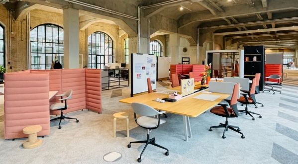 Offene Musterfläche im Vitra BETA Event Space mit verschiedenen Arbeits- und Besprechungsbereichen, abgeschirmten Sitznischen und flexiblen Arbeitsplätzen in historischer Industriearchitektur.