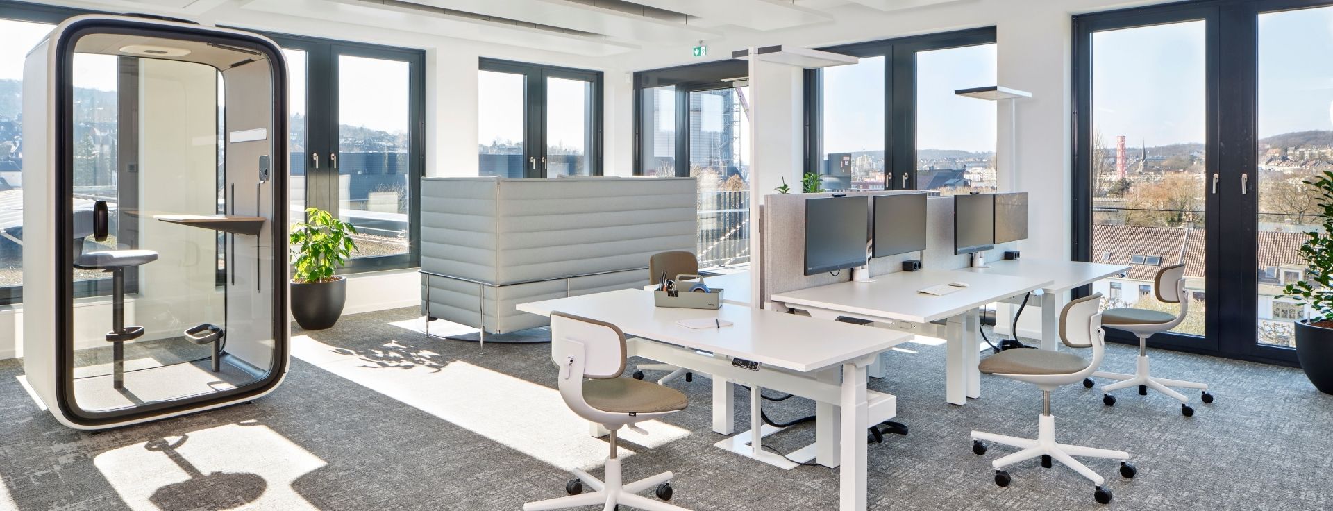 Arbeitsbereich mit integrierter Begrünung durch Pflanztröge, natürlichem Tageslicht und ruhigen Zonen für fokussiertes Arbeiten.