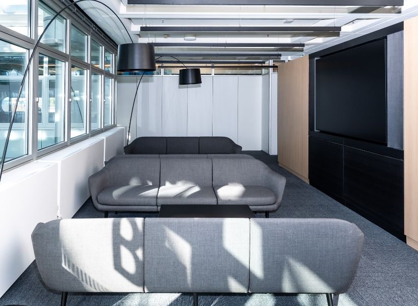 Loungebereich mit Sofalandschaft und Medientechnik als ergänzende Zone für Austausch, Pausen und informelle Besprechungen.