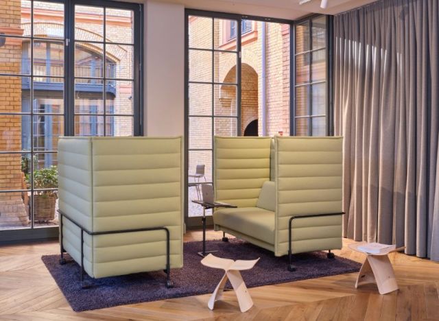 Zwei gegenüberstehende Alcoven-Sitzmöbel auf einem Teppich mit kleinem Tisch zwischen den Sitzplätzen vor großen Fensterfronten.