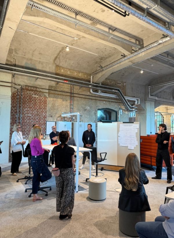 Workshop-Situation mit mobilen Whiteboards, Arbeitsflächen und Teilnehmenden im offenen Raum.