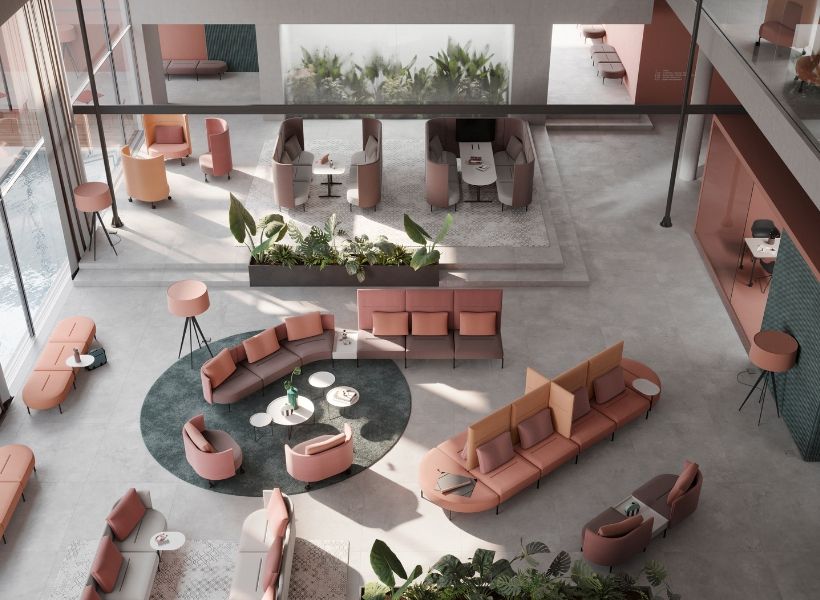 Offene Arbeitslandschaft mit zentraler Lounge, Besprechungszonen und begrünten Bereichen als Treffpunkt für Austausch und Zusammenarbeit.