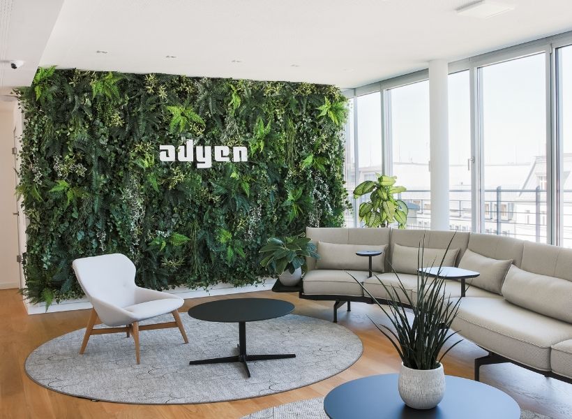 Loungebereich mit großflächiger vertikaler Begrünung, ergänzenden Pflanzen und ruhiger Atmosphäre für Erholung und informellen Austausch.