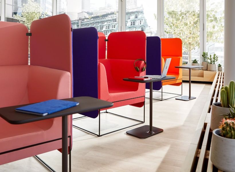 Farbig gestaltete Rückzugsnischen mit kleinen Arbeitstischen in einem hellen Bürobereich.