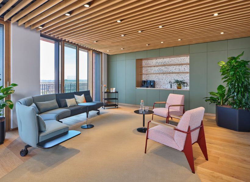 Heller Bürobereich mit Arbeitsplatz, Loungemodulen, farbigen Sitznischen und dekorativen Elementen.