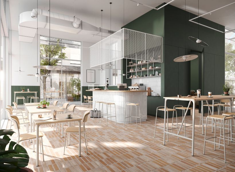 Helles Workcafé mit Kaffeebar, verschiedenen Sitzbereichen und Hochtischen sowie zentralem Tresen für Pausen, informellen Austausch und mobiles Arbeiten.