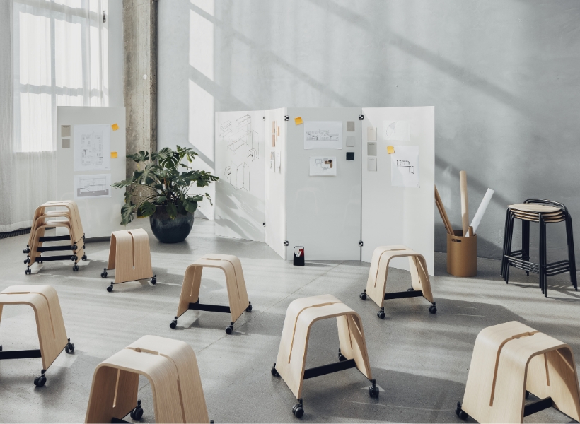Workshop-Situation mit mobilen Hockern, Stellwänden und Skizzenmaterialien für flexible Zusammenarbeit und kreative Arbeitsprozesse im Büro.