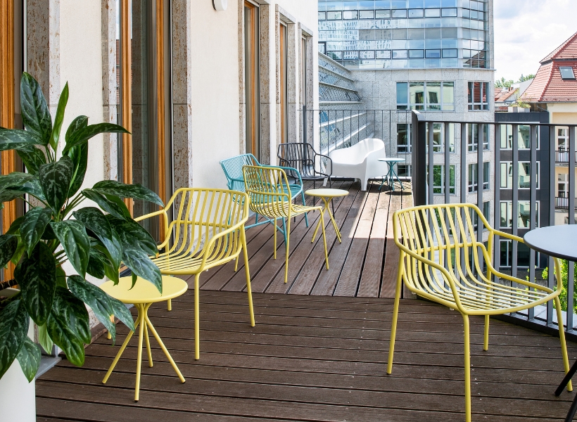 Außenbereich mit bepflanztem Balkon, Sitzgelegenheiten und ergänzender Begrünung für Pausen im Freien.