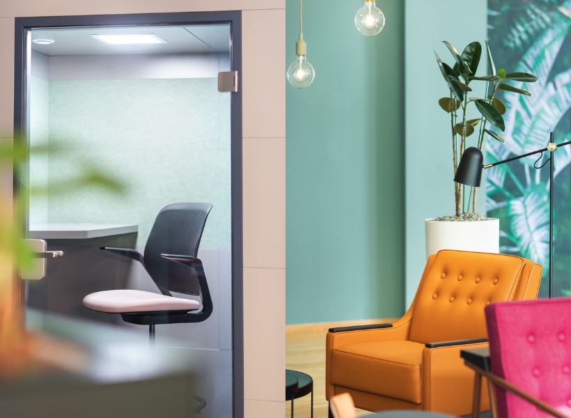 Moderner Bürobereich mit orangefarbenem Sessel, Glas‑Besprechungsraum und grünen Akzenten.